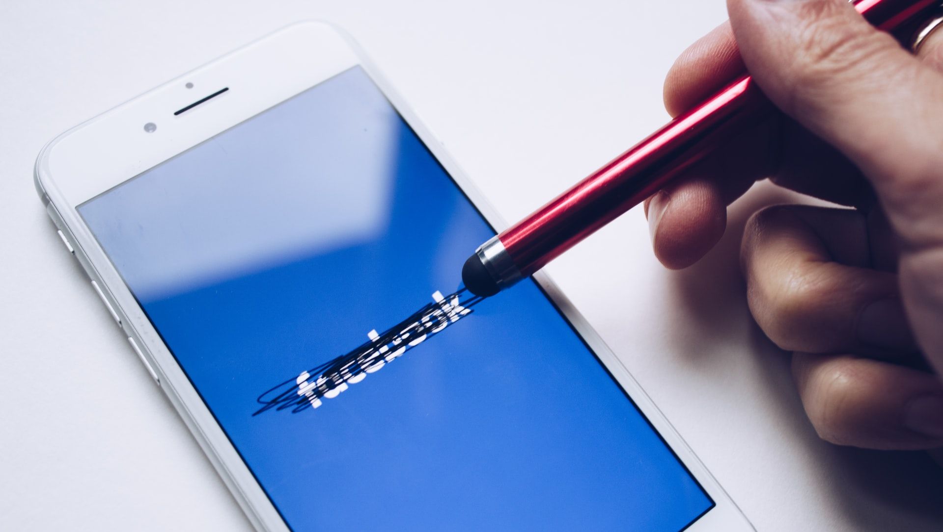 Person som stryker over Facebook-logo på telefonskjermen