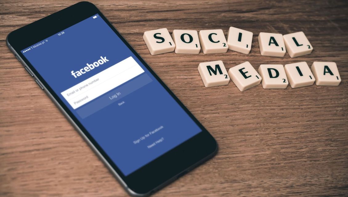 Telefon logget inn på Facebook, med teksten "Social media" ved siden av i Scrabble bokstaver