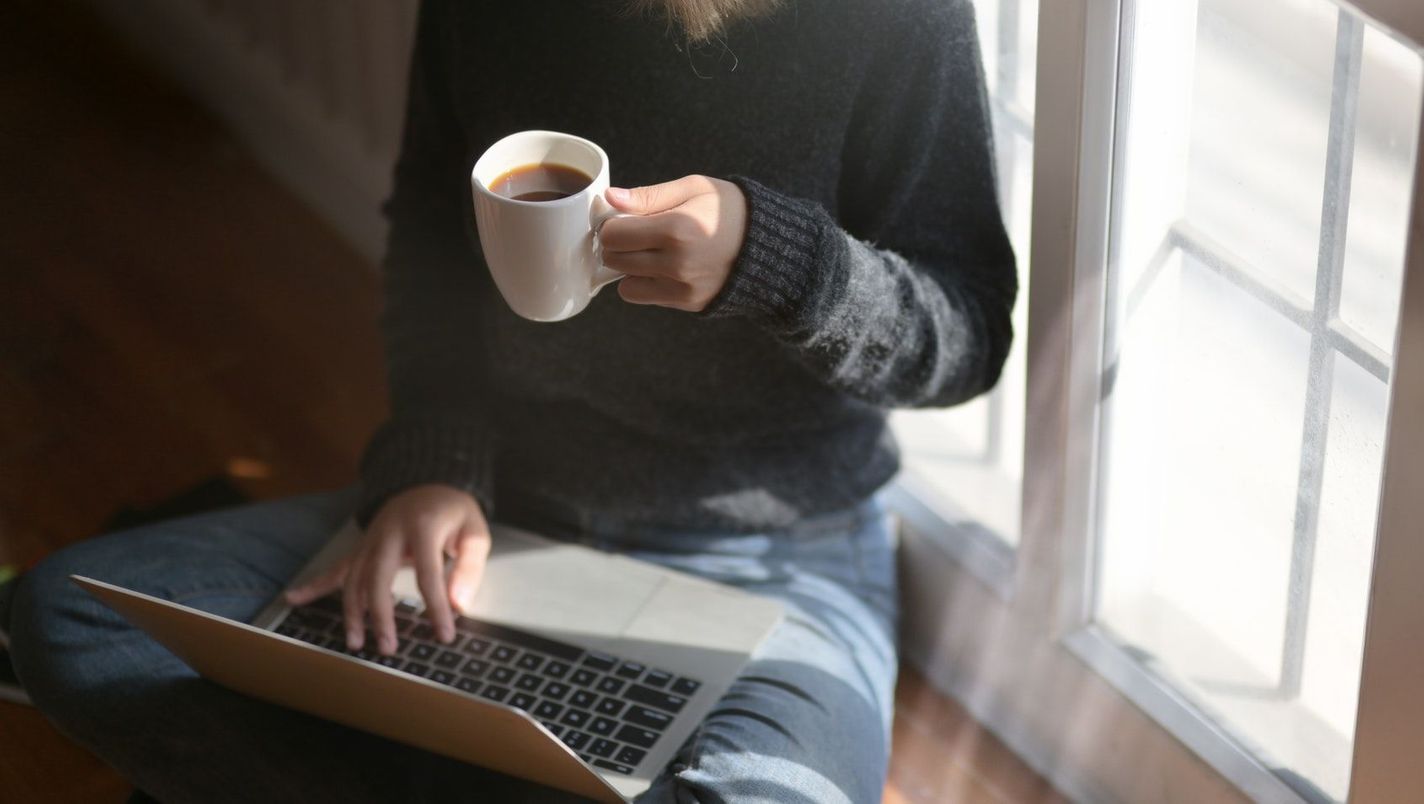 Ansatt som sjekker SEO på datamaskin mens en drikker kaffe